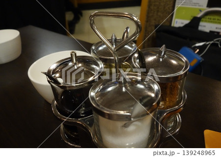 Metal Condiment Shakers with Spoons on Table 139248965