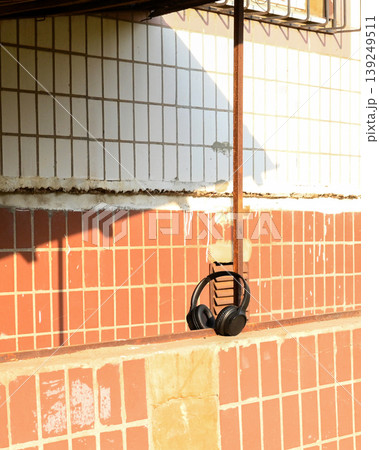 black headphones lying on the old brick wall of the house 139249511
