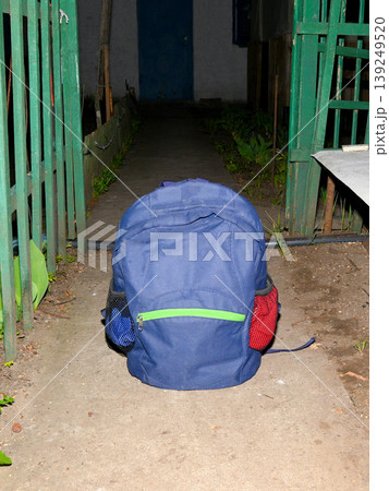 blue textile backpack stands on the ground in front of the entrance to the yard blue textile backpack stands on the ground in front of the entrance to the yard 139249520