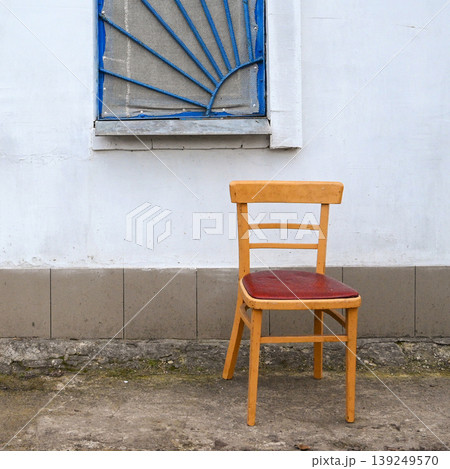 yellow chair against a white wall with a blue window yellow chair against a white wall with a blue window 139249570