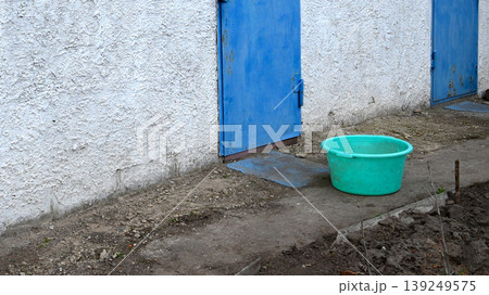 plastic basin in the yard near a wall and blue doors plastic basin in the yard near a wall and blue doors 139249575