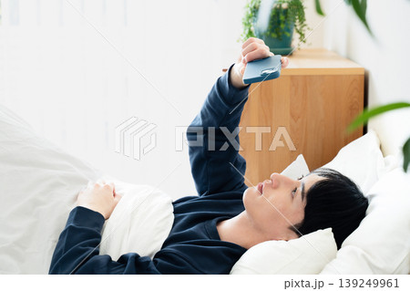 ベッドでスマホを見る若い男性 ベッドでスマホを見る若い男性 139249961