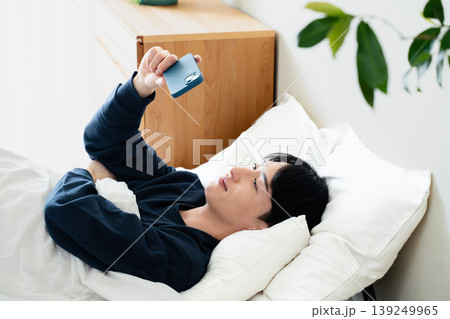 ベッドでスマホを見る若い男性 ベッドでスマホを見る若い男性 139249965