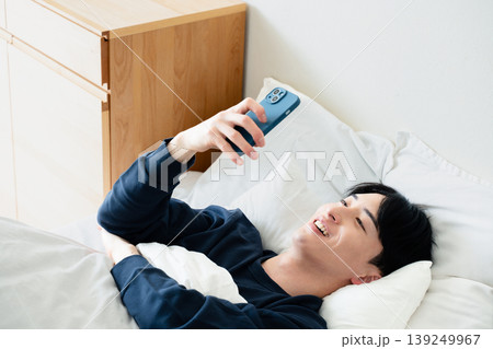 ベッドでスマホを見る若い男性 ベッドでスマホを見る若い男性 139249967