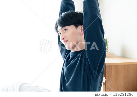 ベッドで伸びをする若い男性 139251286