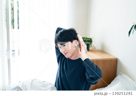 ベッドで伸びをする若い男性 139251291
