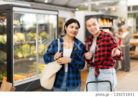 Two young women talk and choosing food in grocery store Two young women talk and choosing food in grocery store 139251631