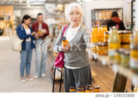 Elderly woman chooses juice in grocery store 139251680