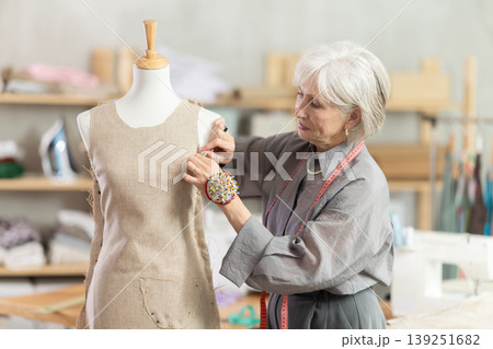 Mature female dressmaker working with mannequin in sewing workshop 139251682