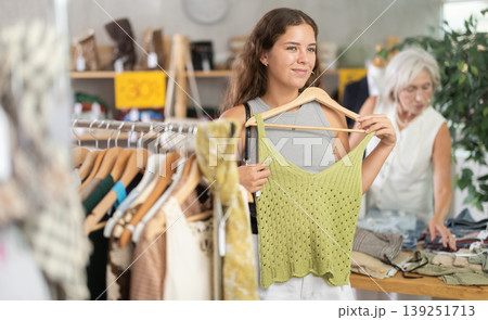 Young woman choosing top in clothing store Young woman choosing top in clothing store 139251713
