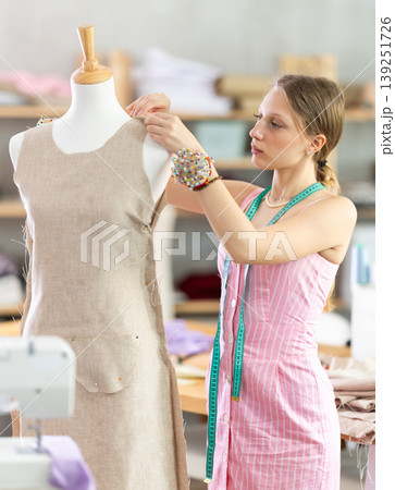 Woman seamstress adjusts clothes on mannequin Woman seamstress adjusts clothes on mannequin 139251726
