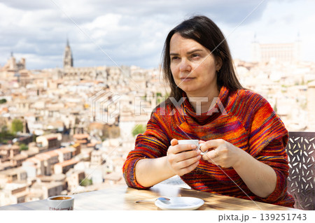 Portrait of a woman traveler sitting at a table and holding a cup of coffee Portrait of a woman traveler sitting at a table and holding a cup of coffee 139251743