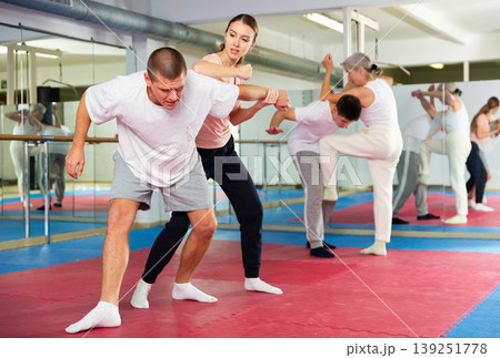 Girl performing elbow strike and wristlock to man in self defence training Girl performing elbow strike and wristlock to man in self defence training 139251778