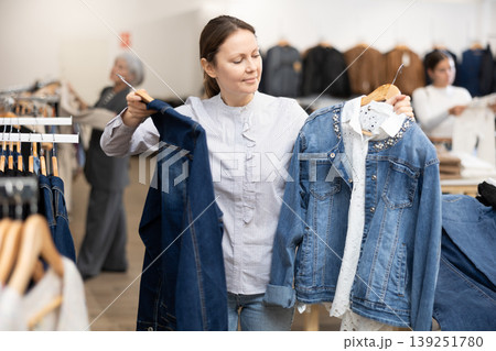 Adult woman choosing denim jacket in store Adult woman choosing denim jacket in store 139251780