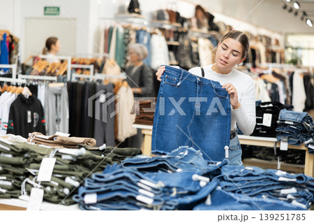 Young girl choosing jean skirt in clothing store Young girl choosing jean skirt in clothing store 139251785