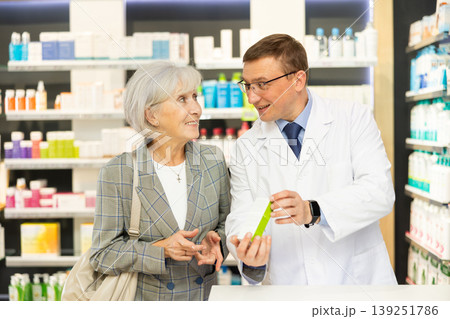Elderly woman client consults with pharmacist which medicinal ointment to buy Elderly woman client consults with pharmacist which medicinal ointment to buy 139251786
