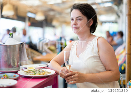 Woman relaxes on terrace of summer cafe and eats grilled sardines Woman relaxes on terrace of summer cafe and eats grilled sardines 139251850