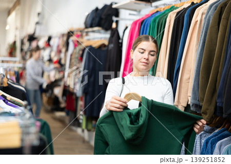 Young woman shopping for warm casual clothing in retail shopping store 139251852