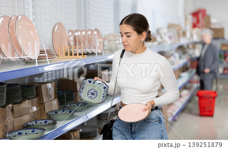 Interested young girl choosing ceramic Asian style plates in store Interested young girl choosing ceramic Asian style plates in store 139251879