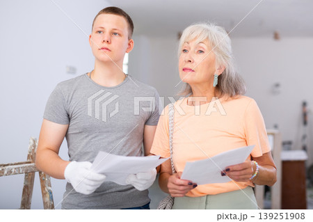 Mature woman is studying documentation with a worker, discussing something Mature woman is studying documentation with a worker, discussing something 139251908