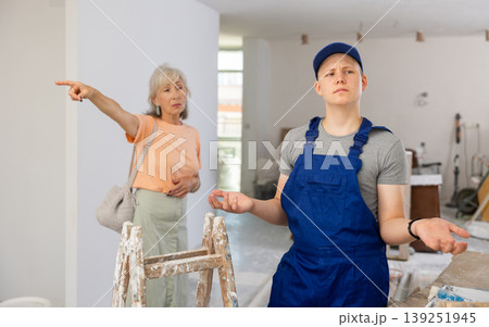 Disgruntled mature woman points out something to a fifteen-year-old worker 139251945