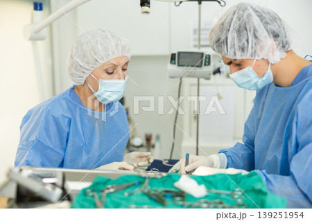 Elderly female veterinarian assisting colleague during surgery at veterinary clinic Elderly female veterinarian assisting colleague during surgery at veterinary clinic 139251954