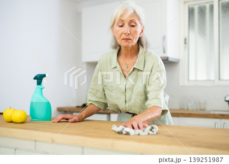 Elderly woman washing kitchen table during cleanup 139251987