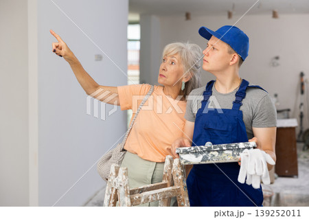 Senior woman discussing work details with teenager boy in constrcuction site Senior woman discussing work details with teenager boy in constrcuction site 139252011