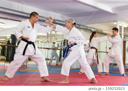 Elderly woman in kimono practicing martial arts techniques with trainer Elderly woman in kimono practicing martial arts techniques with trainer 139252023