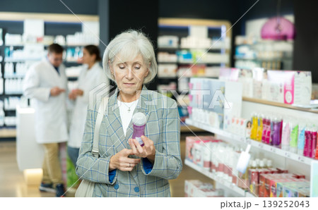 Mature woman chooses lubricant and intimate hygiene items in pharmacy Mature woman chooses lubricant and intimate hygiene items in pharmacy 139252043
