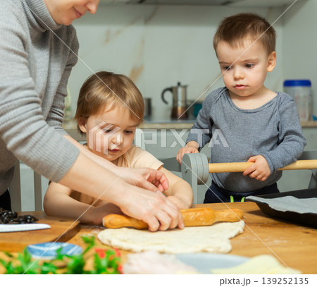 Mother and two young boys making pizza together in home kitchen 139252135