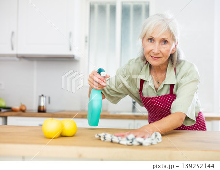 Mature woman cleaning kitchen table at home 139252144