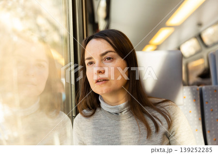 Female traveler looking at landscapes outside window in train Female traveler looking at landscapes outside window in train 139252285