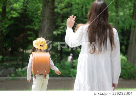 新緑の中で元気に手を振るランドセル姿の女の子 小学校入学と登校「いってらっしゃい」と親が子供を見送る 新緑の中で元気に手を振るランドセル姿の女の子 小学校入学と登校「いってらっしゃい」と親が子供を見送る 139252304