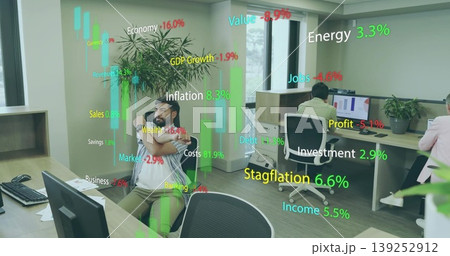 Stretching Indian man wearing striped shirt leaning in open office with floating finance metrics Stretching Indian man wearing striped shirt leaning in open office with floating finance metrics 139252912