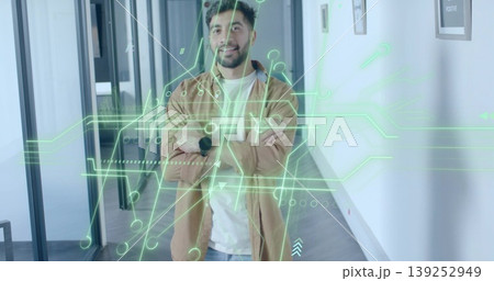 Standing man wearing brown overshirt crossing arms in office hallway, with circuit hologram overlay Standing man wearing brown overshirt crossing arms in office hallway, with circuit hologram overlay 139252949