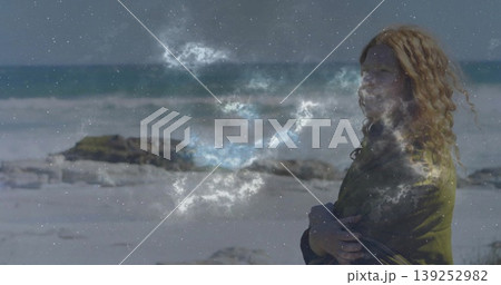 Standing woman crossing arms on beach, with olive jacket, red hair and nebula overlay, copy space Standing woman crossing arms on beach, with olive jacket, red hair and nebula overlay, copy space 139252982