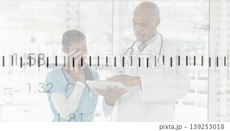 Two professionals wearing coat and scrubs studying chart in hospital corridor, with stethoscopes Two professionals wearing coat and scrubs studying chart in hospital corridor, with stethoscopes 139253018