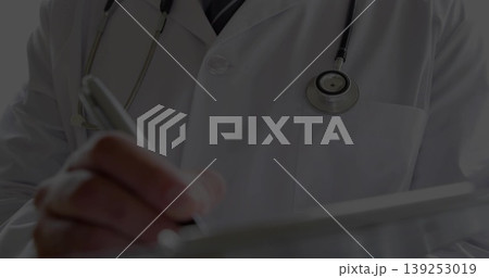 Doctor reviewing patient records on tablet in clinic, with stylus, white lab coat and stethoscope Doctor reviewing patient records on tablet in clinic, with stylus, white lab coat and stethoscope 139253019