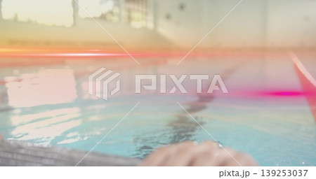 Hand gripping metal pool edge at swimming pool, showing window glare on lane stripe, copy space 139253037