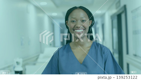 Smiling nurse wearing navy scrubs standing in well-lit hospital corridor with medical cart, doors Smiling nurse wearing navy scrubs standing in well-lit hospital corridor with medical cart, doors 139253122