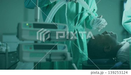 Anesthetist in scrubs holding anesthesia mask over patient in OR, with infusion pumps, copy space Anesthetist in scrubs holding anesthesia mask over patient in OR, with infusion pumps, copy space 139253124