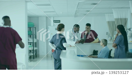 Gathering six healthcare workers reviewing charts at nurse station, with tablet and monitors Gathering six healthcare workers reviewing charts at nurse station, with tablet and monitors 139253127