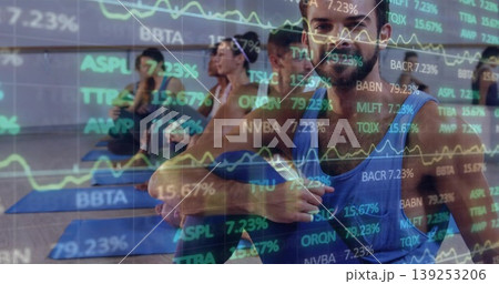 Twisting man on yoga mat in studio with mirror reflection, financial charts overlay, copy space Twisting man on yoga mat in studio with mirror reflection, financial charts overlay, copy space 139253206