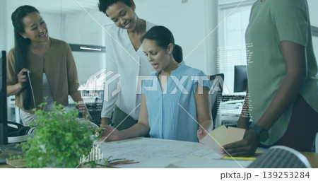 Reviewing Middle Eastern architect pointing at design plans in office with laptop and swatches 139253284