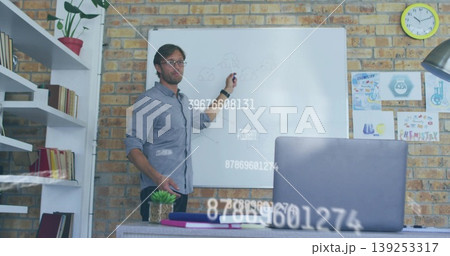 Sketching network diagram wearing glasses and blue shirt on whiteboard in office, featuring laptop Sketching network diagram wearing glasses and blue shirt on whiteboard in office, featuring laptop 139253317