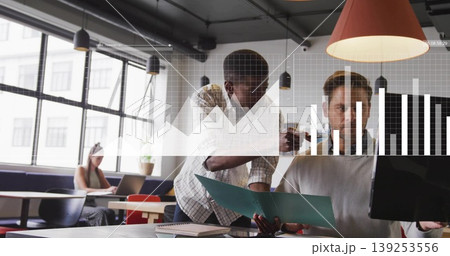 Leaning Black male and white male reviewing documents at modern office, with folder and monitor Leaning Black male and white male reviewing documents at modern office, with folder and monitor 139253556