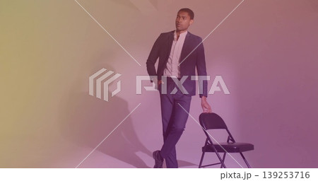 Leaning casually man wearing tailored dark suit and white shirt in studio with black folding chair Leaning casually man wearing tailored dark suit and white shirt in studio with black folding chair 139253716