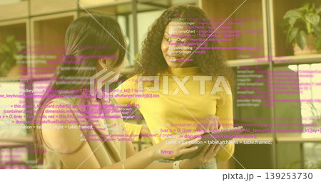 Reviewing tablet, developers wearing casual tops in office, code overlay and bookshelf with plant Reviewing tablet, developers wearing casual tops in office, code overlay and bookshelf with plant 139253730