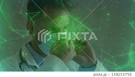 Adjusting male doctor securing surgical mask in clinic, with stethoscope and globe network visuals Adjusting male doctor securing surgical mask in clinic, with stethoscope and globe network visuals 139253758